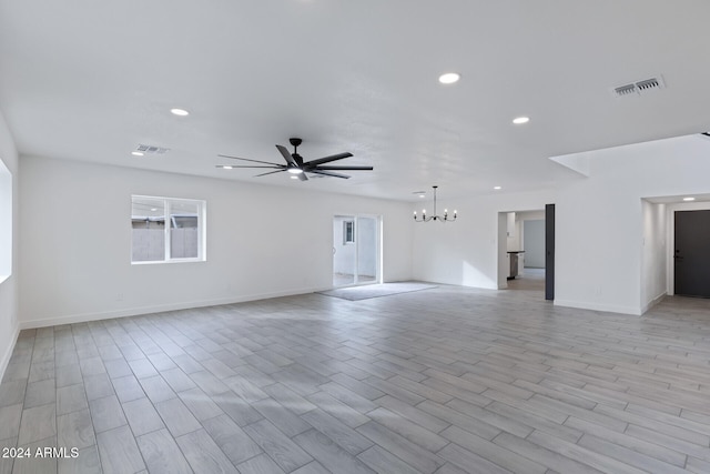 empty room with ceiling fan with notable chandelier and light hardwood / wood-style floors