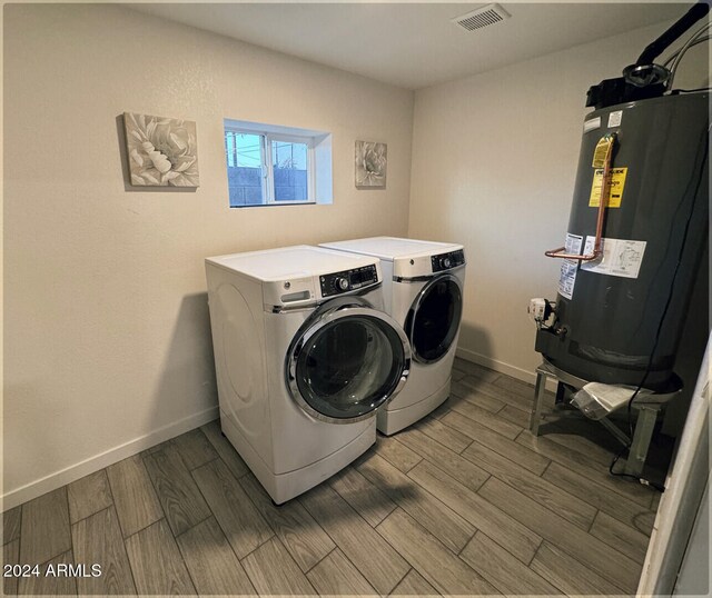 clothes washing area with light hardwood / wood-style floors, gas water heater, and washing machine and clothes dryer