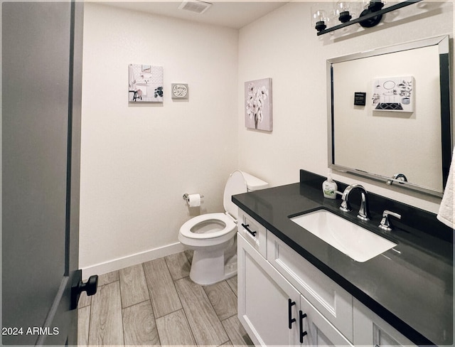 bathroom featuring toilet, vanity, and hardwood / wood-style floors