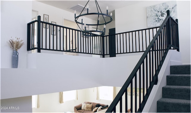 stairway featuring a high ceiling and an inviting chandelier