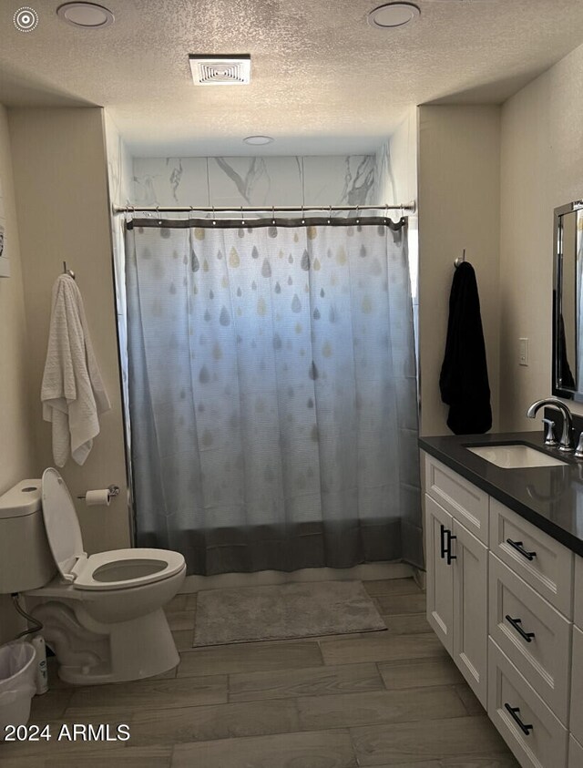 full bathroom featuring hardwood / wood-style floors, vanity, a textured ceiling, and toilet