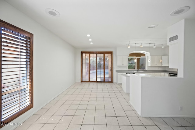 kitchen featuring light tile patterned floors, light countertops, visible vents, white cabinetry, and a peninsula