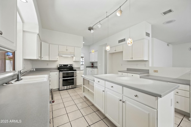 kitchen with light tile patterned floors, range with two ovens, under cabinet range hood, a sink, and visible vents