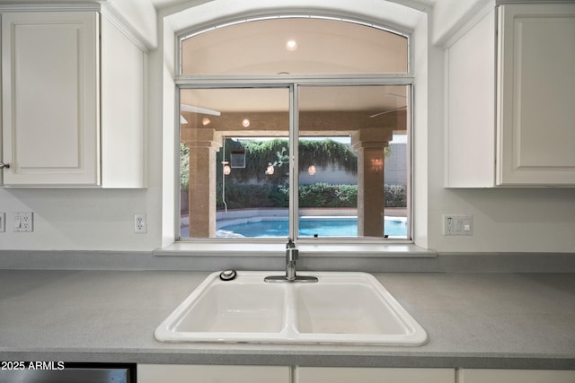 kitchen with dishwasher, a sink, and white cabinets