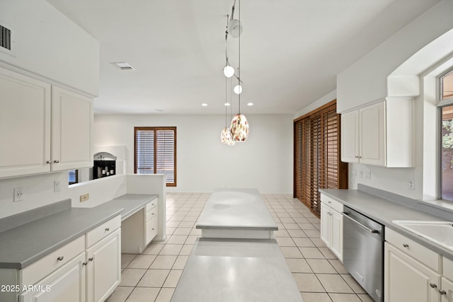 kitchen featuring stainless steel dishwasher, light tile patterned flooring, white cabinetry, and decorative light fixtures