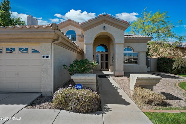 view of front facade with a garage, a tiled roof, and stucco siding