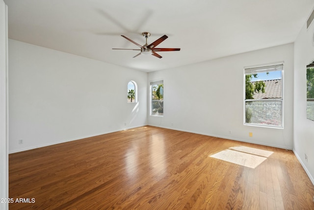 spare room featuring ceiling fan, light wood-style flooring, and baseboards