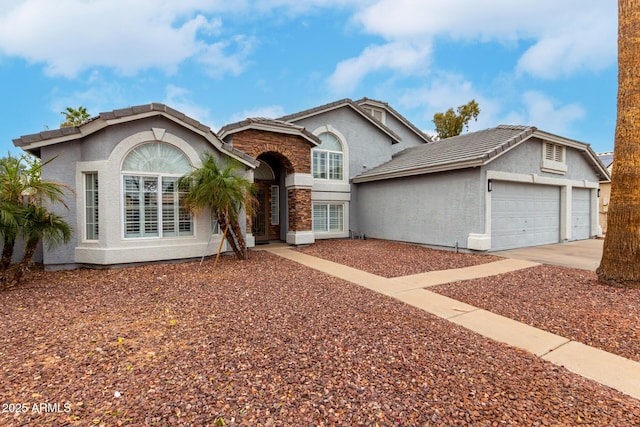 view of front facade with concrete driveway, an attached garage, a tiled roof, and stucco siding