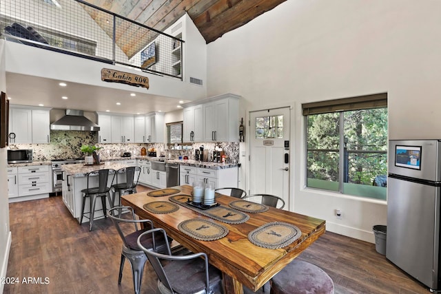 dining area with a towering ceiling and dark wood-type flooring