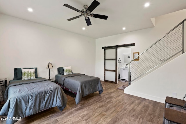 bedroom with ceiling fan, ensuite bath, hardwood / wood-style floors, and a barn door