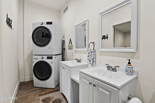 laundry area with stacked washer / drying machine, dark hardwood / wood-style flooring, and sink