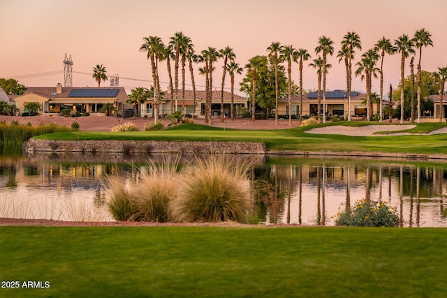 surrounding community with a water view and a lawn