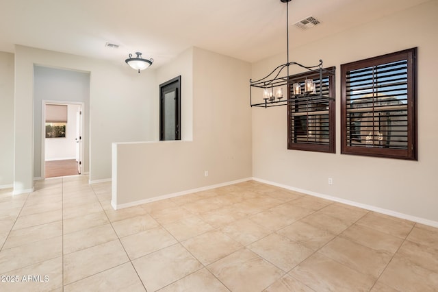 tiled empty room featuring a chandelier