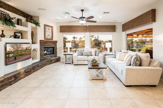 living room with a fireplace, ceiling fan, built in features, and light tile patterned floors