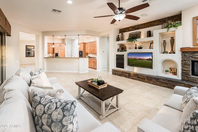 tiled living room featuring built in shelves, ceiling fan, and a fireplace