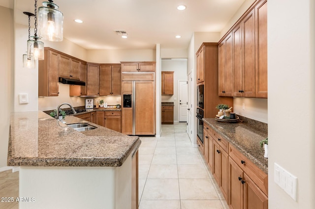 kitchen with kitchen peninsula, sink, pendant lighting, built in appliances, and light tile patterned flooring