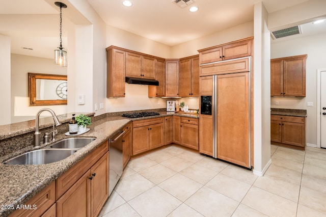 kitchen featuring pendant lighting, dishwasher, sink, dark stone countertops, and paneled fridge