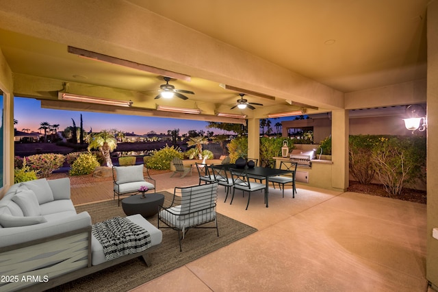 patio terrace at dusk featuring ceiling fan, area for grilling, and an outdoor hangout area