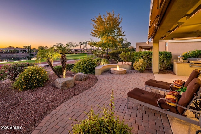 patio terrace at dusk featuring grilling area and a fire pit