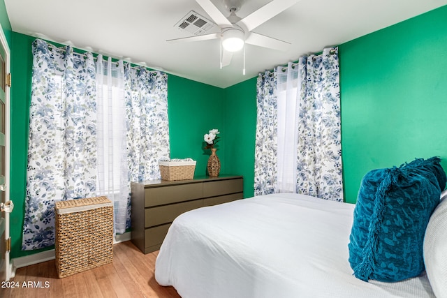 bedroom with ceiling fan, multiple windows, and light hardwood / wood-style flooring