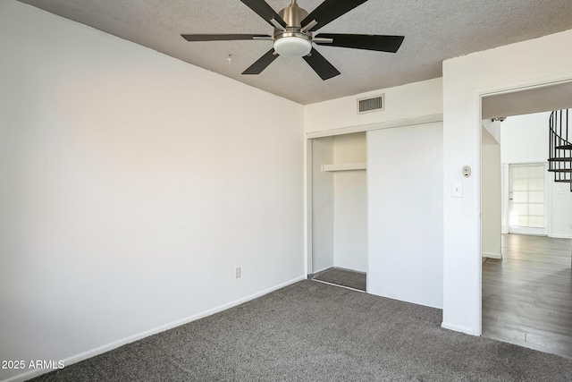 unfurnished bedroom featuring ceiling fan, dark carpet, a textured ceiling, and a closet