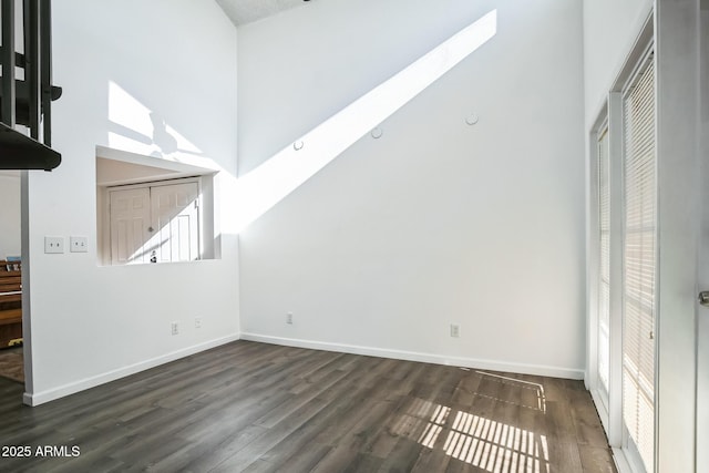 interior space featuring a towering ceiling, a skylight, and dark wood-type flooring