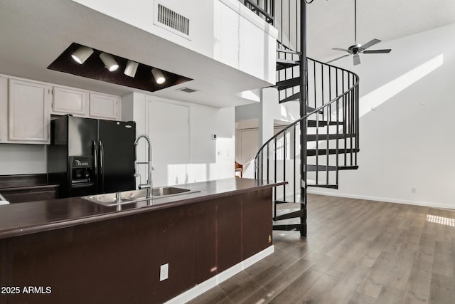 kitchen featuring white cabinets, black fridge, sink, ceiling fan, and dark hardwood / wood-style flooring