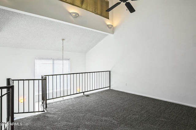 carpeted empty room with vaulted ceiling with beams, ceiling fan, and a textured ceiling