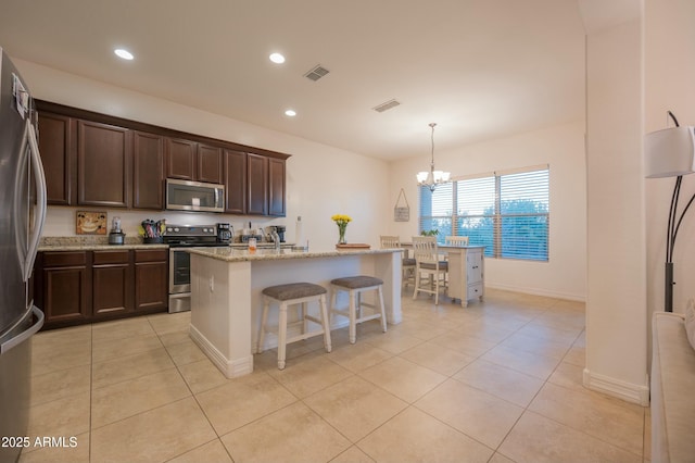 4571 N Arbor Way, Buckeye, AZ 85396 - kitchen featuring appliances with stainless steel finishes, light tile patterned floors, dark brown cabinetry, light stone countertops, and recessed lighting