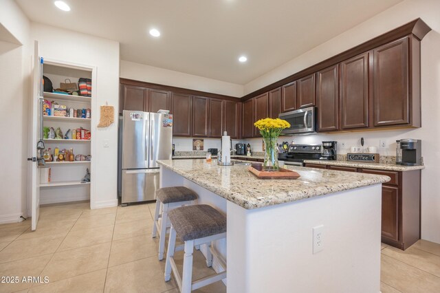 4571 N Arbor Way, Buckeye, AZ 85396 - kitchen with appliances with stainless steel finishes, light tile patterned floors, light stone countertops, a kitchen island with sink, and recessed lighting
