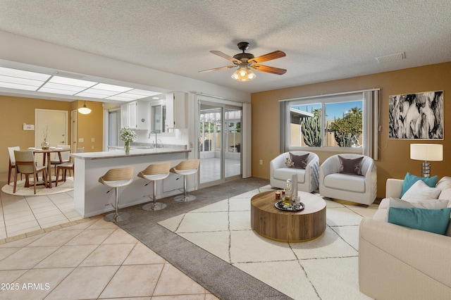 tiled living room featuring sink, ceiling fan, and a textured ceiling