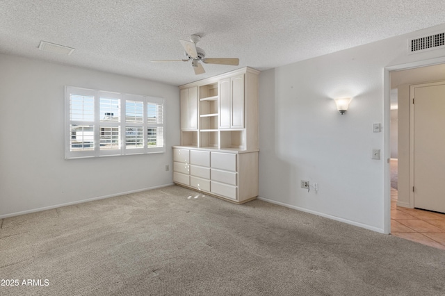 carpeted spare room featuring ceiling fan and a textured ceiling