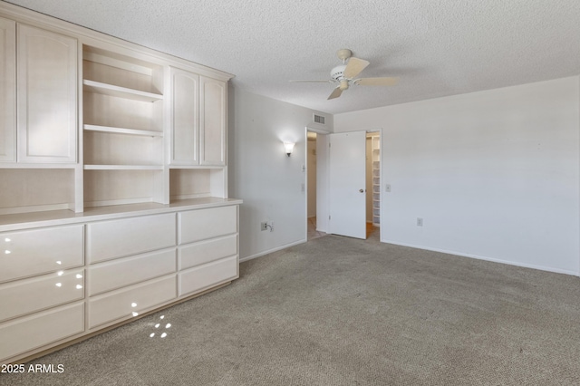 empty room featuring a textured ceiling, light colored carpet, and ceiling fan