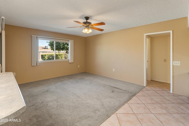 empty room with ceiling fan, a textured ceiling, and light tile patterned flooring