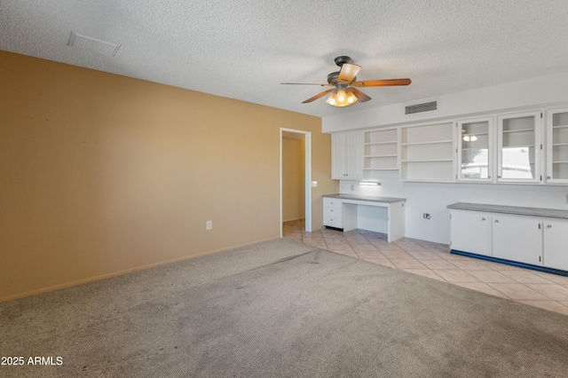 unfurnished living room with a textured ceiling, light colored carpet, and ceiling fan