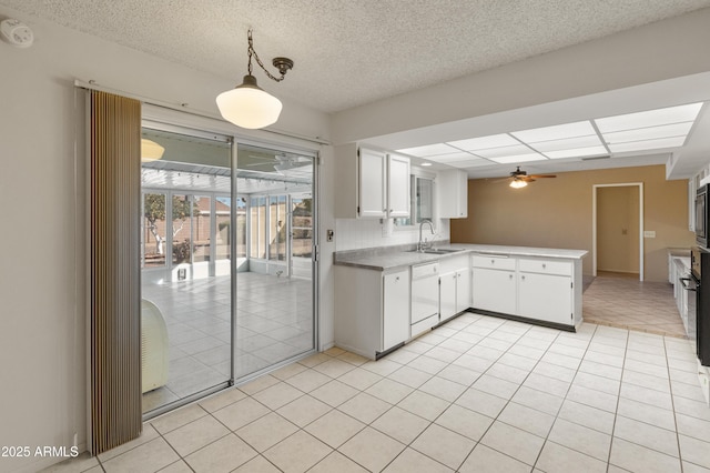 kitchen featuring white cabinets, decorative light fixtures, kitchen peninsula, and dishwasher