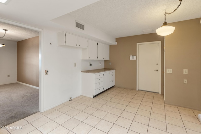 kitchen featuring light colored carpet, pendant lighting, white cabinets, and a textured ceiling