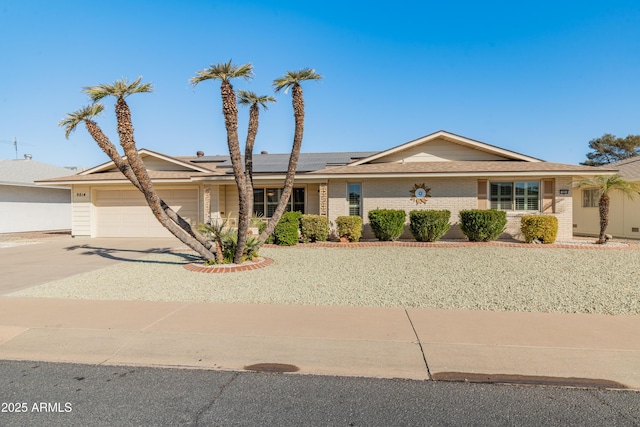 ranch-style house with a garage and solar panels