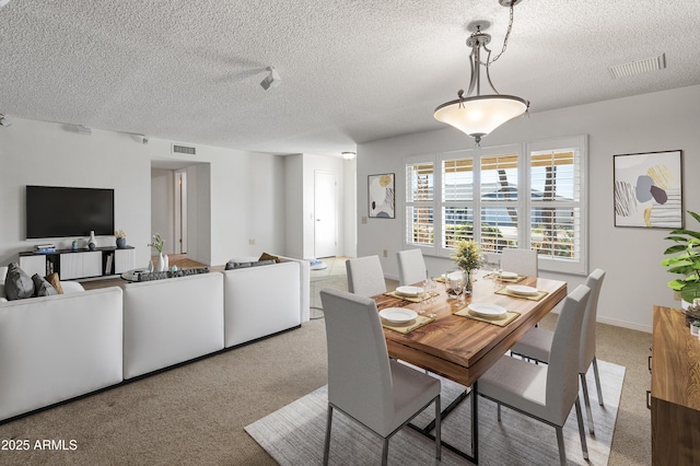 carpeted dining room featuring a textured ceiling