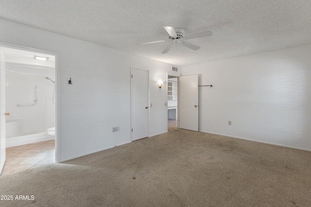 empty room with ceiling fan, light colored carpet, and a textured ceiling