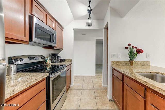 kitchen featuring lofted ceiling, light tile patterned floors, stainless steel appliances, light stone countertops, and decorative light fixtures