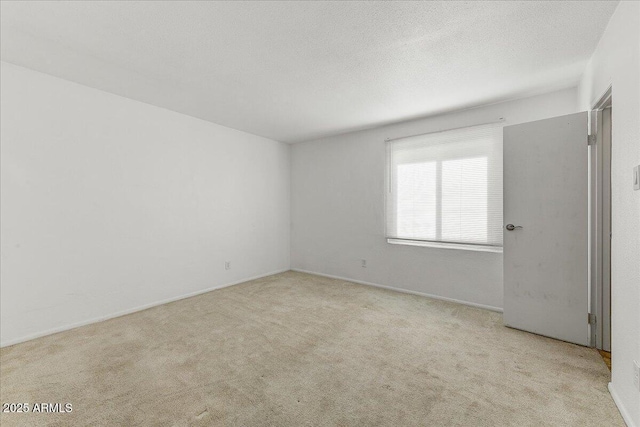 empty room featuring light colored carpet and a textured ceiling