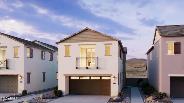 view of front of house with an attached garage, stucco siding, concrete driveway, a balcony, and a tiled roof