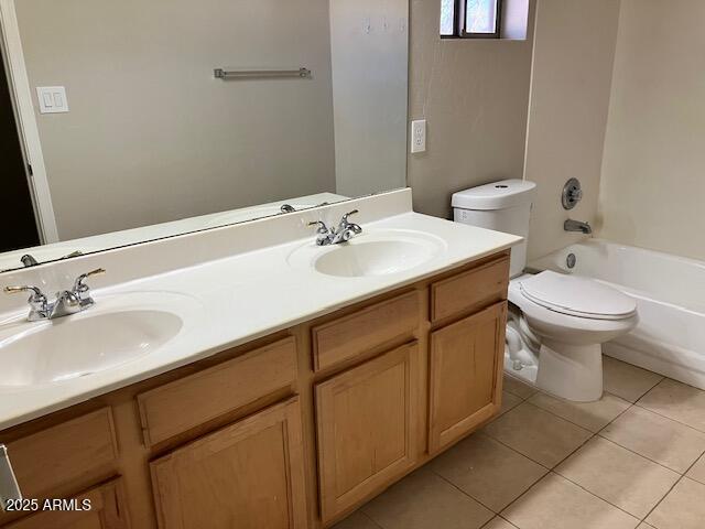 bathroom featuring tile patterned flooring, a sink, double vanity, and toilet