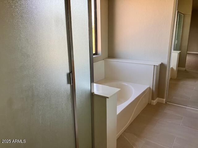 bathroom featuring tile patterned flooring, a shower with door, and a garden tub