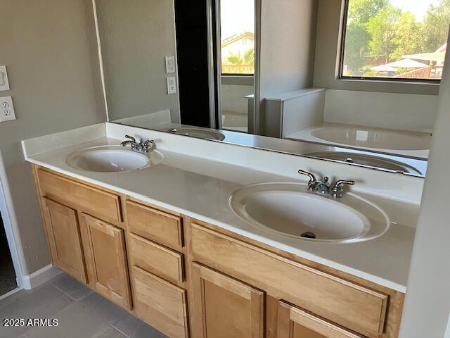 bathroom featuring a bath, double vanity, a sink, and tile patterned flooring
