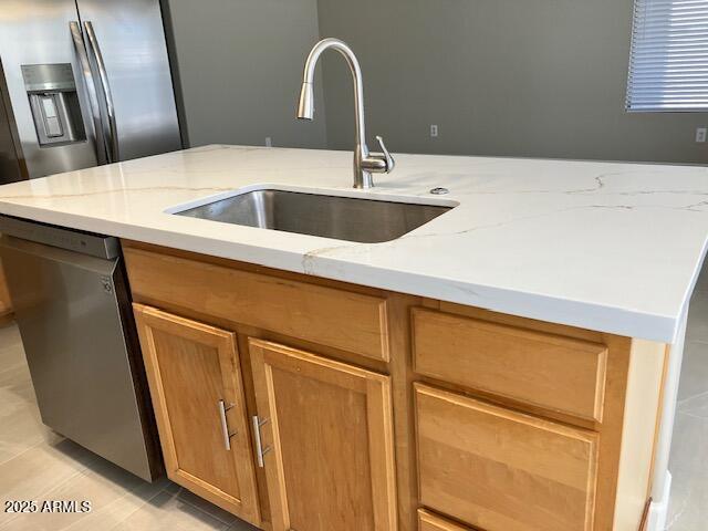 kitchen with brown cabinetry, dishwasher, a sink, light stone counters, and light tile patterned floors