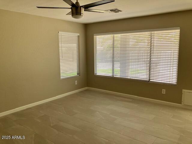 unfurnished room with a ceiling fan, baseboards, and visible vents