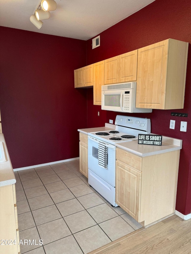 kitchen with light brown cabinetry, white appliances, and light tile patterned floors