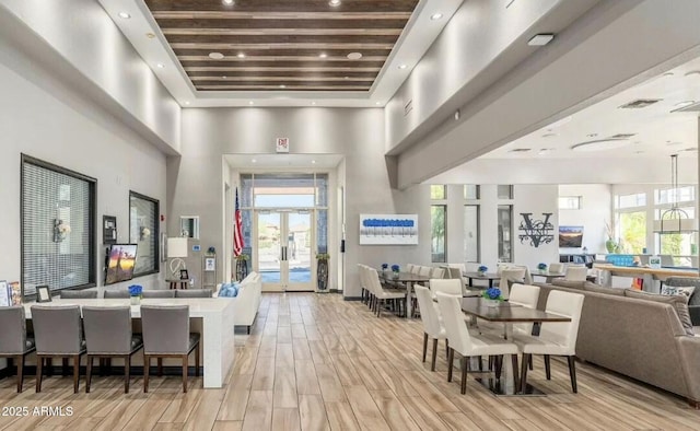 interior space featuring a towering ceiling, plenty of natural light, and french doors